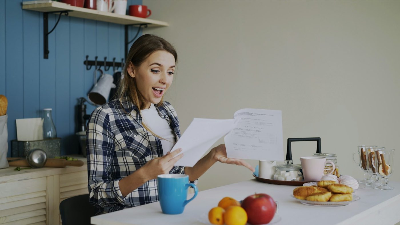 A woman reading a letter at the kitchen table